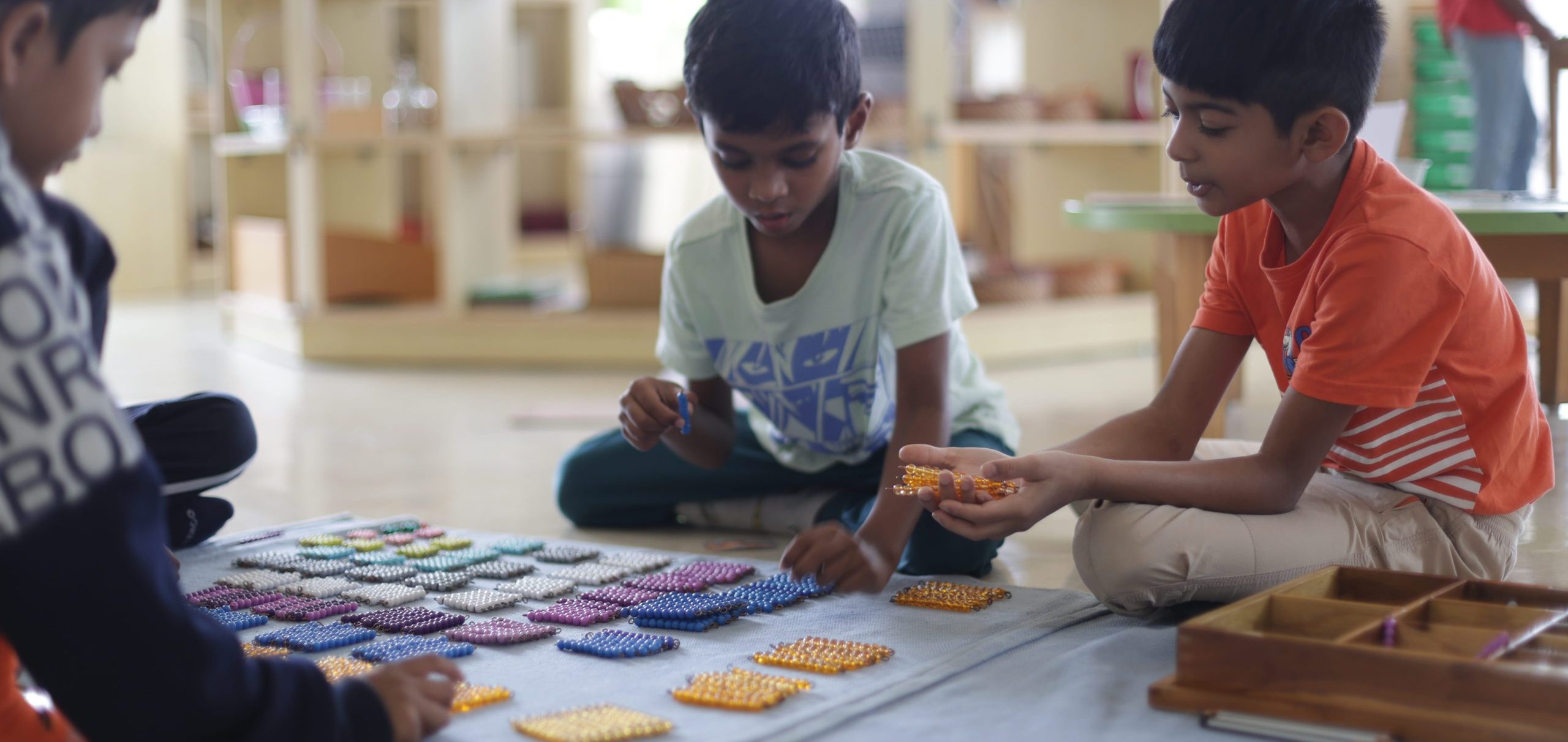 Child-led learning Montessori in practice — a group of children working independently with a hands-on material on their elementary environment at Blue Blocks Montessori School in Hyderabad
